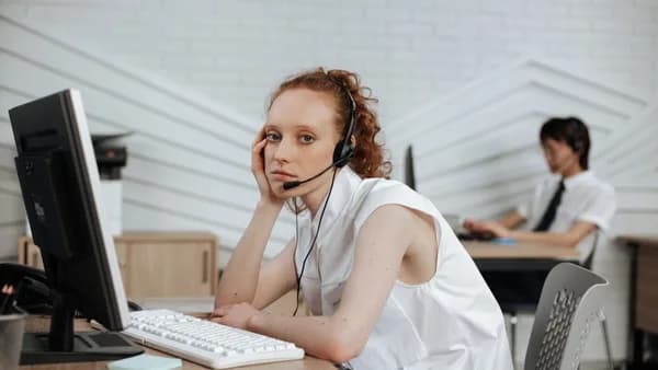 Focused call center agent with headset working at a modern office desk.