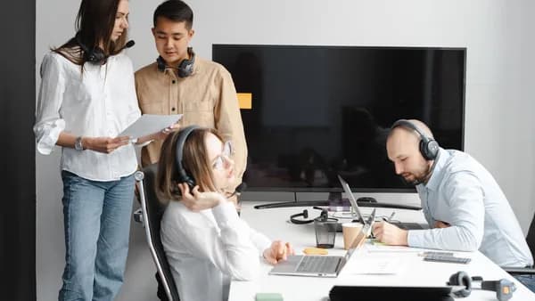 Diverse team of professionals collaborating in a modern office with tech gadgets and headsets.