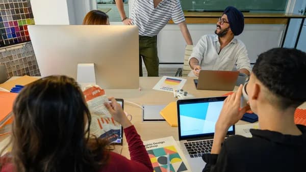 A group of diverse professionals collaborate on a design project in a modern office setting.