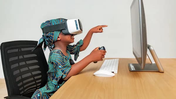 Young child using a VR headset and controller at a desk, engaging with technology.