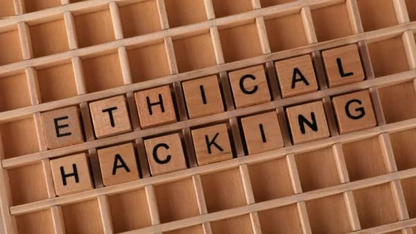 Wooden letter blocks spelling 'Ethical Hacking' on a grid background, symbolizing cybersecurity.