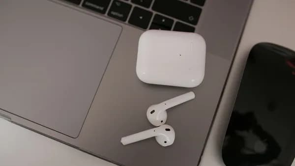 Close-up of wireless earbuds and case on a laptop, highlighting modern tech usage.