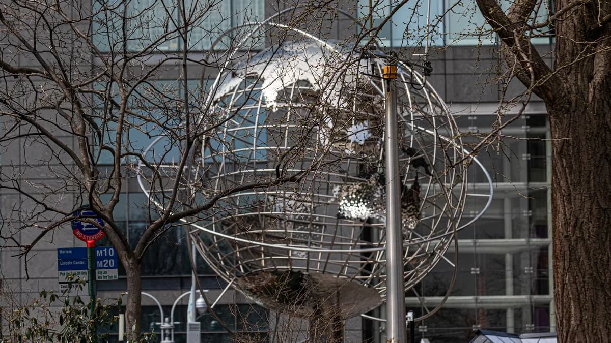 The metallic globe sculpture at Columbus Circle, New York, surrounded by wintry trees.