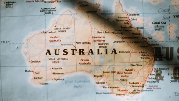Closeup of political map of Australia with cities and regions with borders surrounded by seas and oceans placed on wall in sunny room