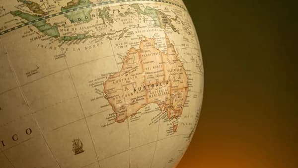 A close-up of a vintage map globe showcasing Australia and Indonesia against a warm background.