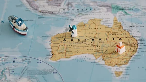 Miniature windmill and ship placed atop a map of Australia, highlighting travel concepts.