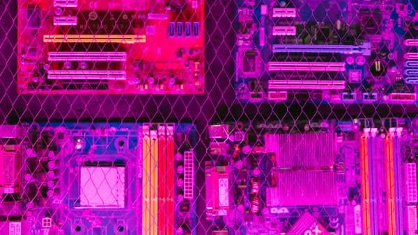 A vibrant image showcasing various circuit boards through a wire mesh, highlighting electronics and technology.