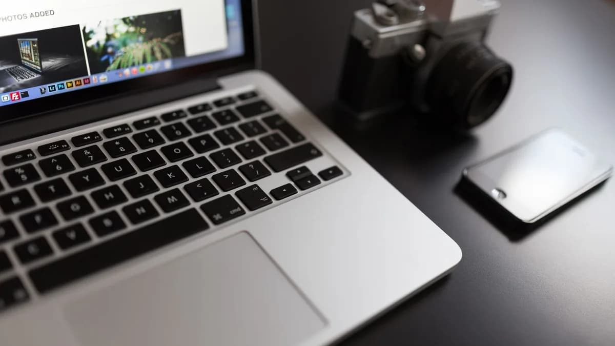 Lifestyle workspace setup with a laptop, camera, and smartphone on a desk.