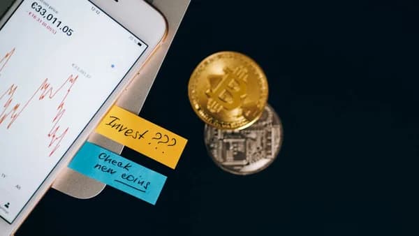 Bitcoin coins and smartphone displaying price chart with investment notes.