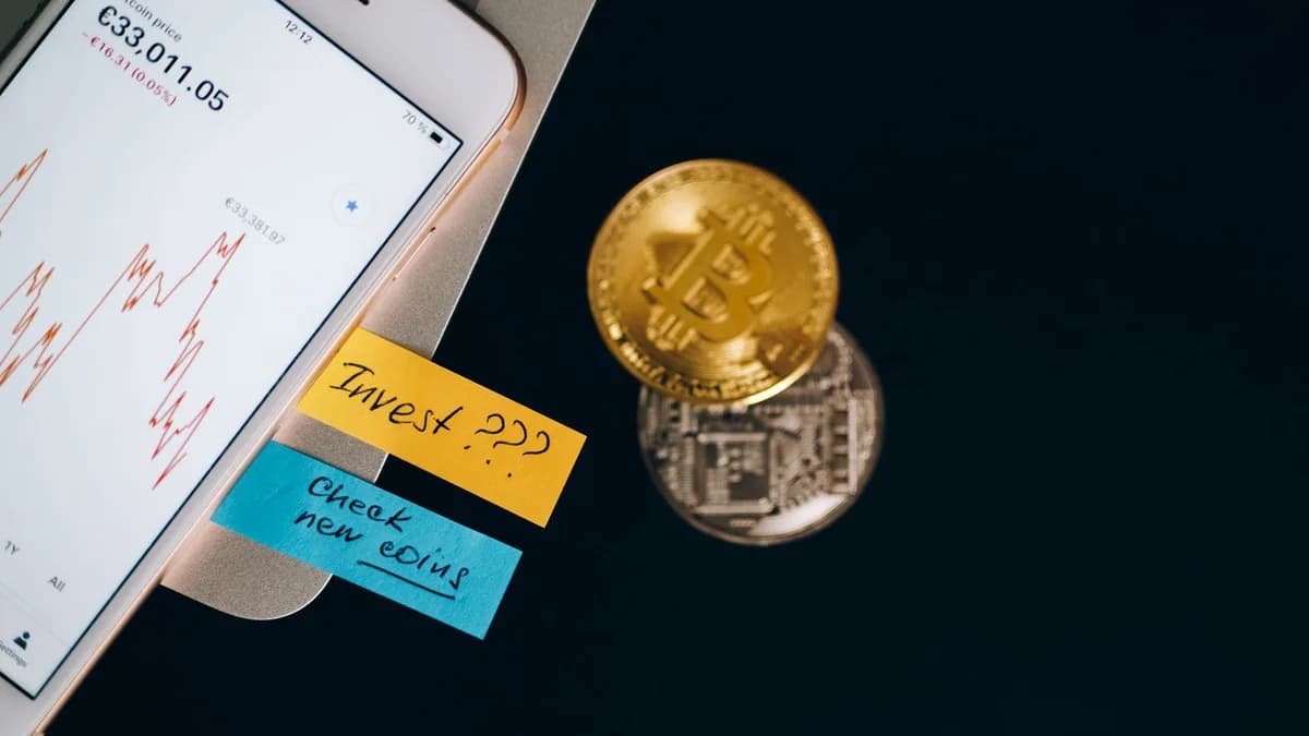 Bitcoin coins and smartphone displaying price chart with investment notes.