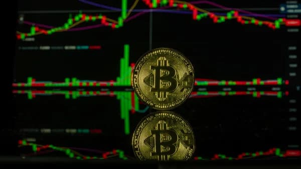 Bitcoin coin against a trading chart background showcasing market trends. Captured in Valencia.