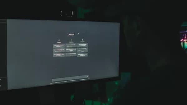 A person interacting with ChatGPT interface on a computer screen in a dimly lit room.