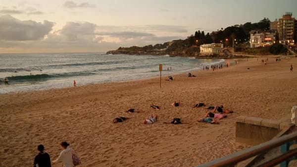People relaxing on Bondi Beach during sunset, capturing a peaceful scene in Sydney, Australia.