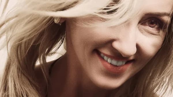 Close-up portrait of a smiling blonde woman with flowing hair.