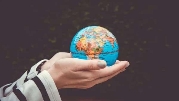 Person holding a small globe in hands, showcasing Earth. Ideal for global concepts or travel themes.