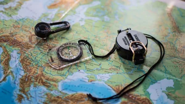 Flat lay of a European map with two compasses, symbolizing travel and exploration.