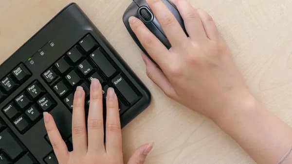 Close-up of hands on a keyboard and mouse, highlighting office work setup.