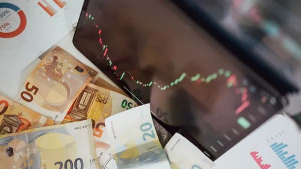 Close-up of euro banknotes with a digital stock market chart displaying a downward trend, symbolizing financial volatility.