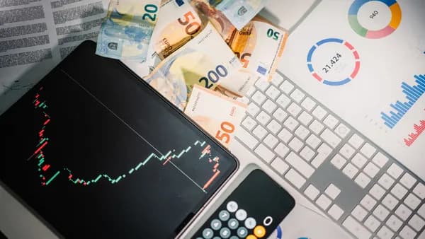 Overhead view of financial tools with Euro banknotes on a desk showing market trends and graphs.