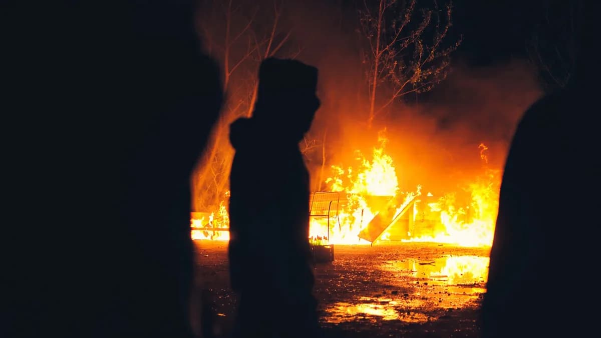 A dramatic night scene showing a silhouette against a blazing fire, capturing the intensity and danger of flames.