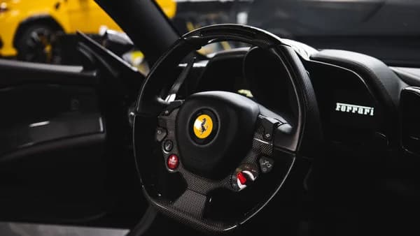 Stylish interior of a luxury car featuring a carbon fiber steering wheel and modern dashboard.