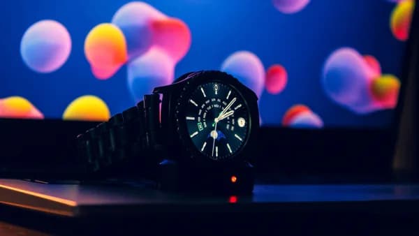 Close-up of a modern wristwatch on a laptop with vibrant digital wallpaper.