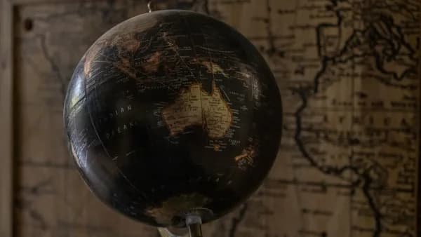 A vintage globe showcases Australia with a sepia world map in the background, offering a classic exploration theme.