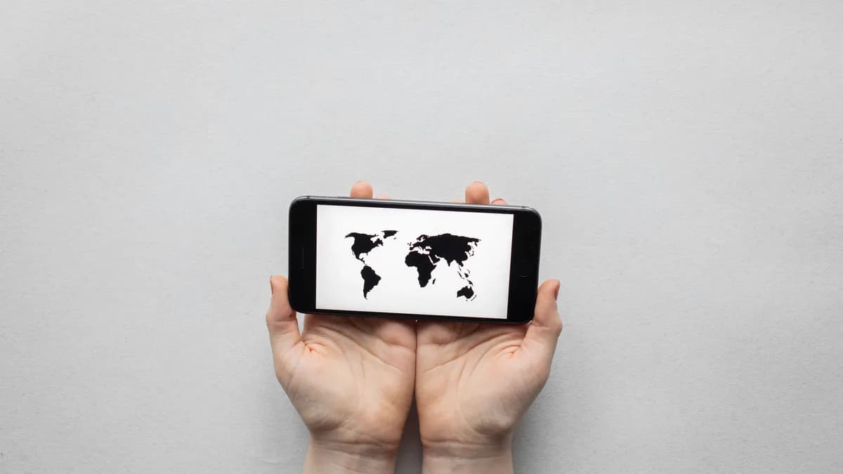 Hands holding a smartphone displaying a world map on a white background.