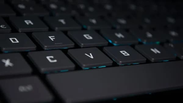 A close-up shot of a backlit keyboard in a dark setting, highlighting the keys.