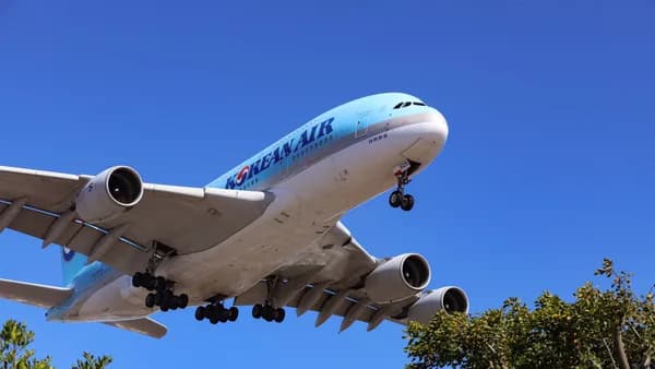 A large airliner flying low against a clear blue sky, captured in daytime.
