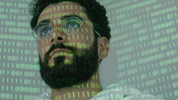 Close-up of a man with glasses and binary code projection, symbolizing cyber security.