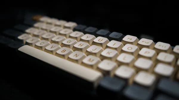 Close-up of a modern mechanical keyboard with white keycaps in a dark setting.