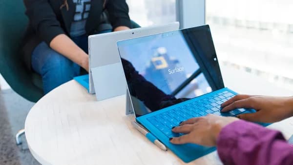 Two people using modern laptops in a bright office setting, showcasing technology in use.