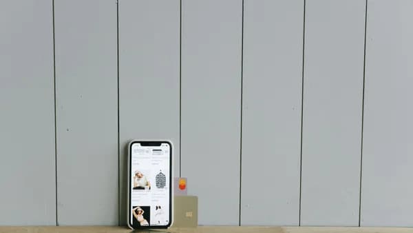 A smartphone displaying an ecommerce site with a credit card, set on a wooden surface, depicting online shopping.