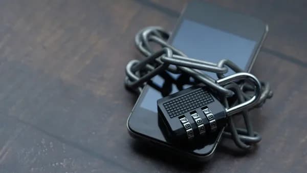 Close-up of a smartphone wrapped in a chain with a padlock, symbolizing strong security.