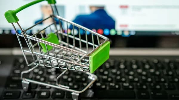 Miniature shopping cart placed on a laptop keyboard, symbolizing online shopping.
