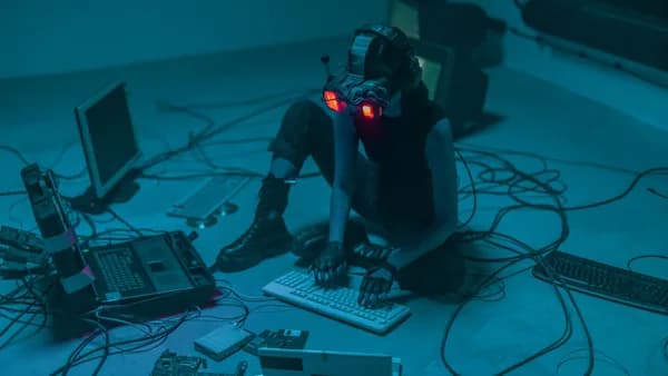 A woman in VR gear surrounded by computers and cables, immersed in a virtual simulation.