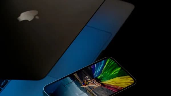 A vibrant smartphone screen displaying colorful imagery next to a laptop in low light.