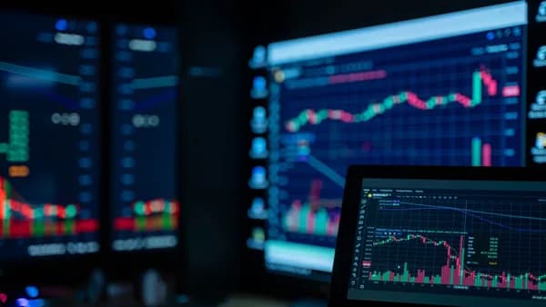 Monitors displaying stock market charts in a dimly lit room, perfect for finance and trading themes.