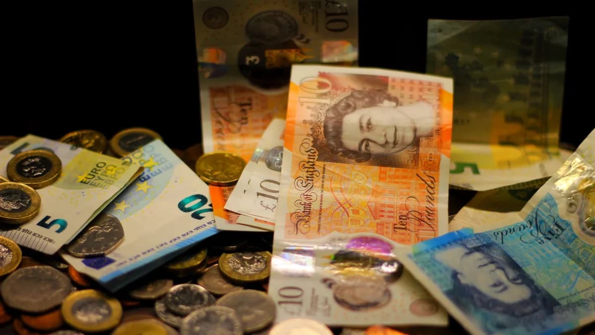 A dark-toned close-up of various Euro and Pound banknotes and coins scattered.
