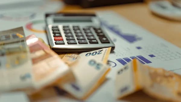 Euro banknotes and calculator on financial documents, focusing on business budget planning.