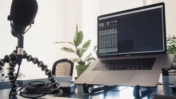 A detailed studio setup featuring a laptop and microphone on a desk for audio production.