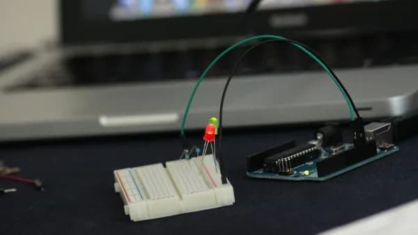 Close-up of an Arduino setup on a breadboard with glowing LED lights indoors.