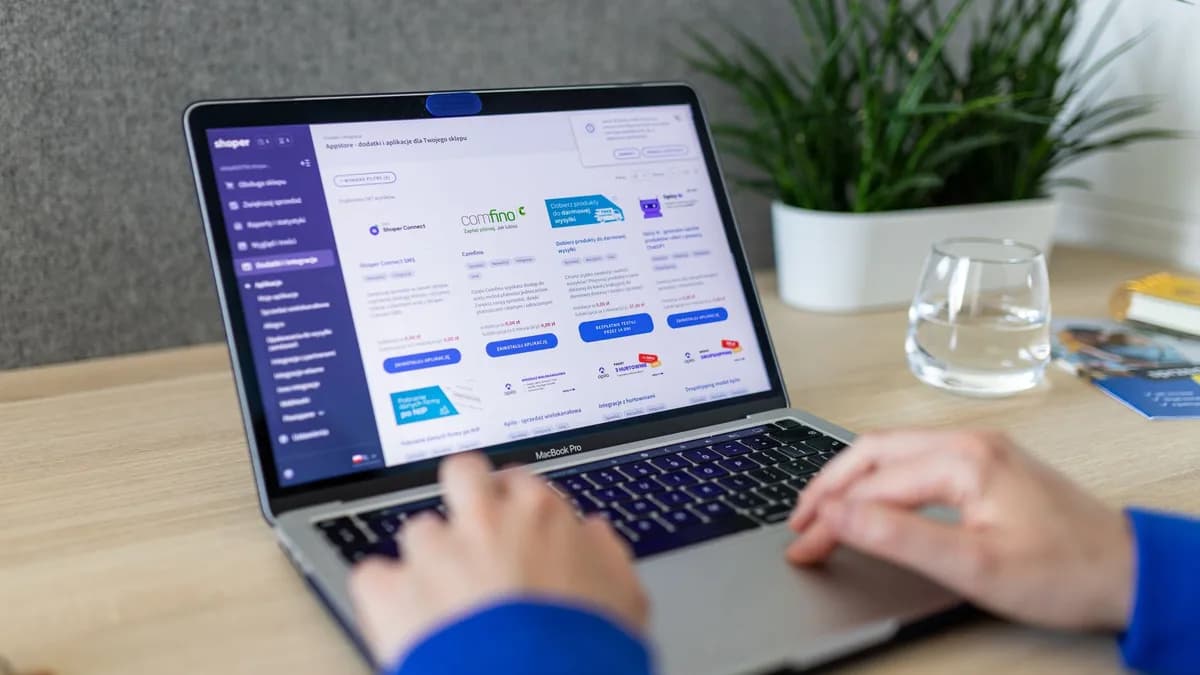 Close-up of hands on a laptop browsing an e-commerce site in a modern office.