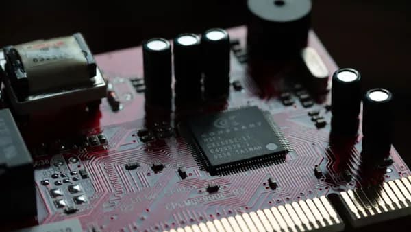 Detailed view of a red circuit board with various electronic components and microchip.