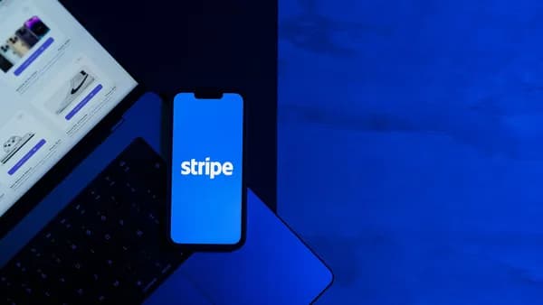 A smartphone displaying the Stripe app placed on a laptop keyboard with a blue monochromatic tone.