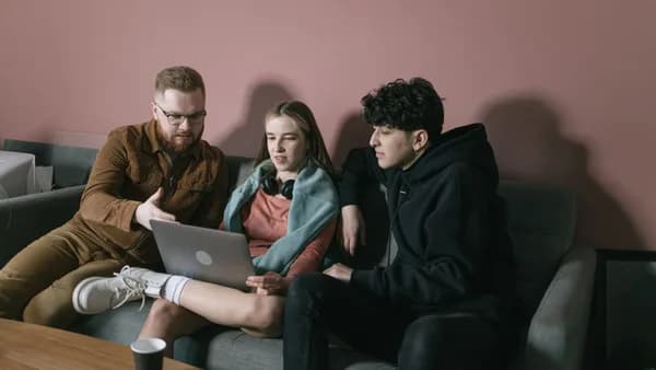 Young team discussing project on laptop in cozy office setting.