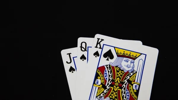 Close-up of Jack, Queen, King of Spades playing cards on black background.
