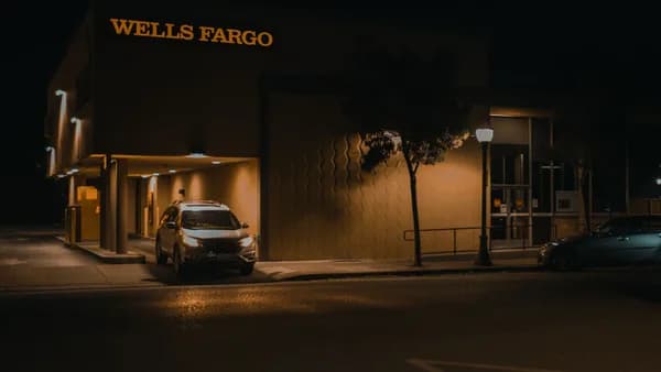 Illuminated Wells Fargo bank branch at night showcasing modern architecture and signage.