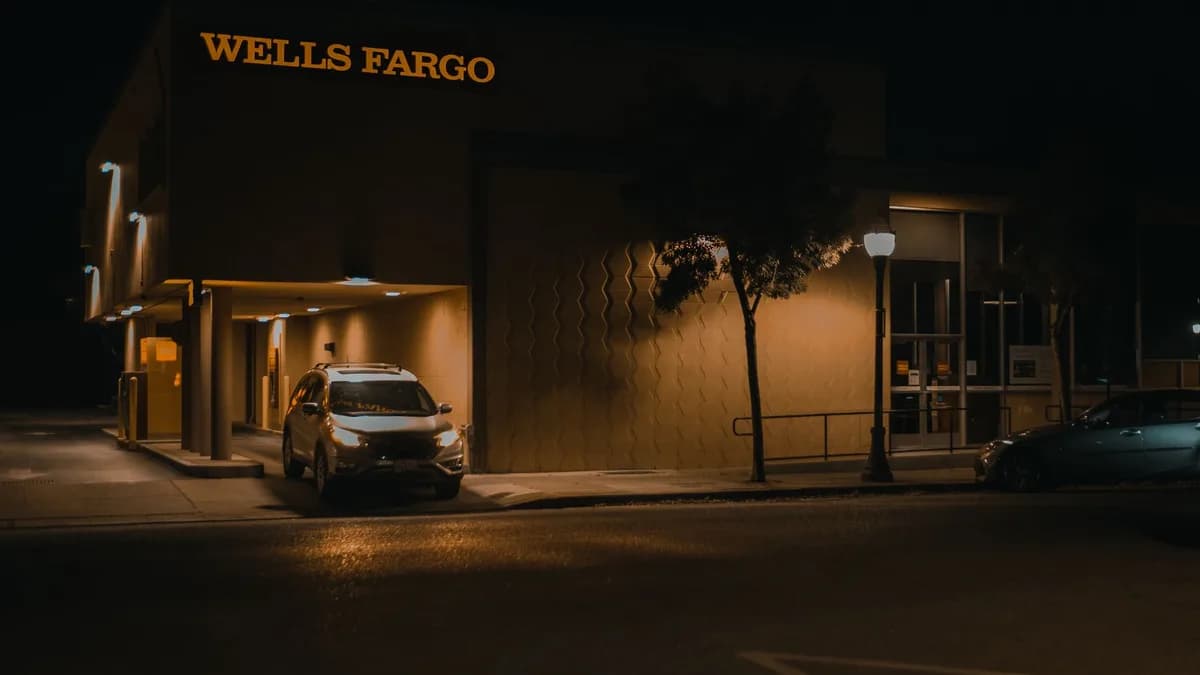 Illuminated Wells Fargo bank branch at night showcasing modern architecture and signage.